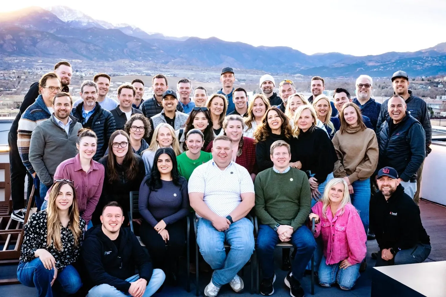 Group photo of about 45 Crane members on a rooftop with mountains in the background