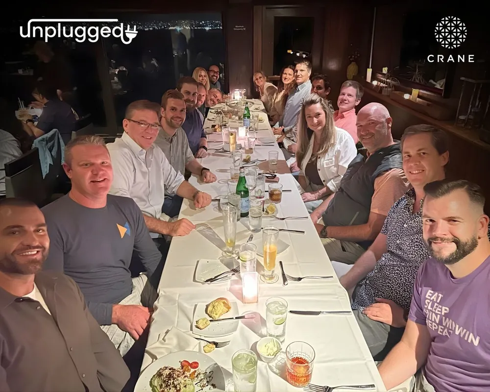 Crane members smiling around a long dinner table at a Crane Unplugged event